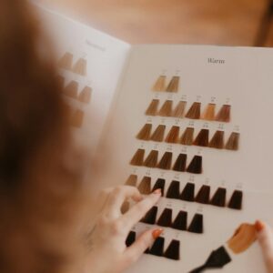 Person selecting hair color from a sample palette in a salon setting.