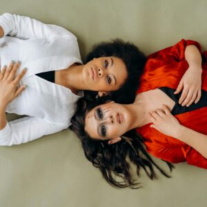Two women in stylish outfits lying on the floor, expressing elegance and poise.